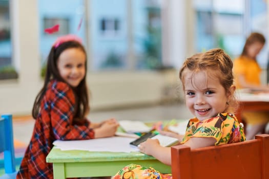 Creative kids during an art class in a daycare center or elementary school classroom drawing with female teacher