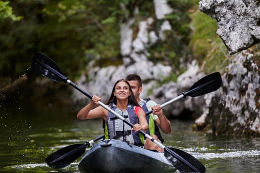 A young couple enjoying an idyllic kayak ride in the middle of a beautiful river surrounded by forest greenery.