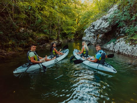 A group of friends enjoying having fun and kayaking while exploring the calm river, surrounding forest and large natural river canyons.