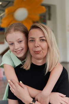 A cute little girl kisses and hugs her mother in preschool. High quality photo