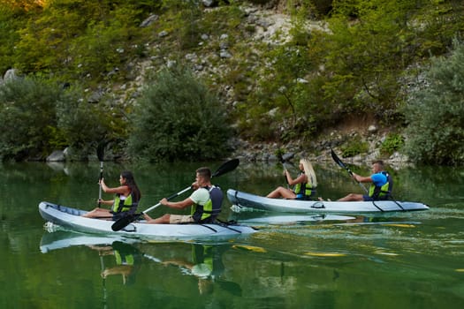 A group of friends enjoying having fun and kayaking while exploring the calm river, surrounding forest and large natural river canyons.