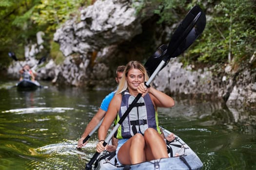 A group of friends enjoying having fun and kayaking while exploring the calm river, surrounding forest and large natural river canyons.