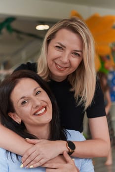 Two women share a heartfelt embrace while at a preschool, showcasing the nurturing and supportive environment for learning and growth.