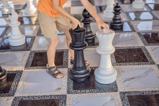 Father and son playing chess spending time together outdoor. Kid play chess.