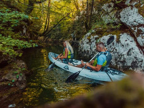 A young couple enjoying an idyllic kayak ride in the middle of a beautiful river surrounded by forest greenery.