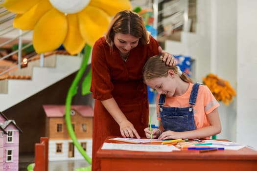 Creative kids during an art class in a daycare center or elementary school classroom drawing with female teacher. High quality photo