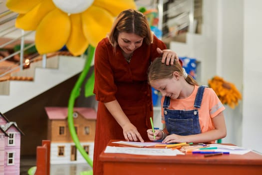 Creative kids during an art class in a daycare center or elementary school classroom drawing with female teacher. High quality photo