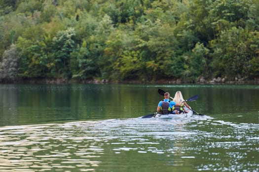 A young couple enjoying an idyllic kayak ride in the middle of a beautiful river surrounded by forest greenery.