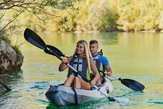 A young couple enjoying an idyllic kayak ride in the middle of a beautiful river surrounded by forest greenery.