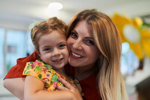 A cute little girl kissing and hugs her mother in preschool. High quality photo