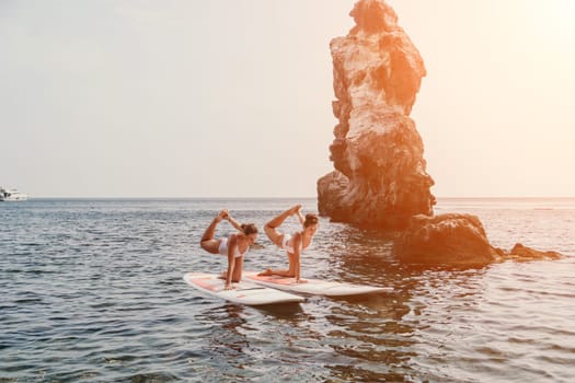 Woman sup yoga. Middle age sporty woman practising yoga pilates on paddle sup surfboard. Female stretching doing workout on sea water. Modern individual hipster outdoor summer sport activity