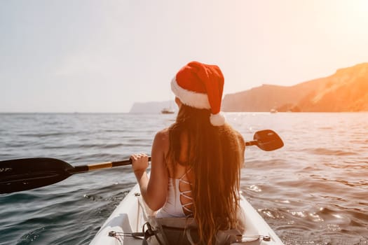 Woman in kayak back view. Happy young woman with long hair floating in transparent kayak on the crystal clear sea. Summer holiday vacation and cheerful female people relaxing having fun on the boat