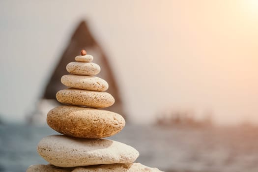 Pyramid stones on the seashore with warm sunset on the sea background. Happy holidays. Pebble beach, calm sea, travel destination. Concept of happy vacation on the sea, meditation, spa, calmness.