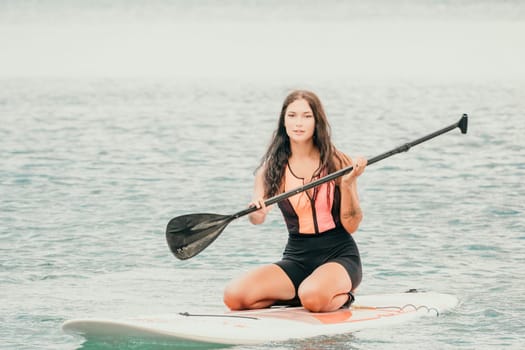 Close up shot of beautiful young caucasian woman with black hair and freckles looking at camera and smiling. Cute woman portrait in a pink bikini posing on a volcanic rock high above the sea