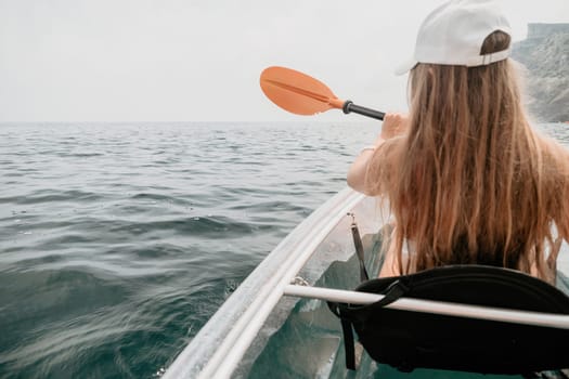 Woman in kayak back view. Happy young woman with long hair floating in transparent kayak on the crystal clear sea. Summer holiday vacation and cheerful female people having fun on the boat.