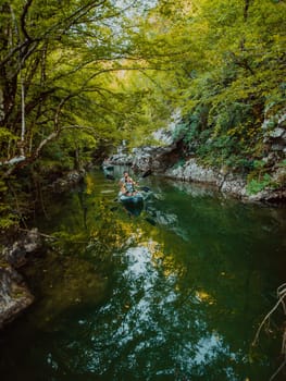 A group of friends enjoying having fun and kayaking while exploring the calm river, surrounding forest and large natural river canyons.