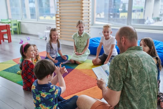 Reading time in an elementary school or kindergarten, a teacher reading a book to children in an elementary school or kindergarten. The concept of pre-school education. Selective focus.