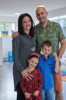 Portrait of a happy family. Photo of parents with children in a modern preschool classroom. Selective focus .
