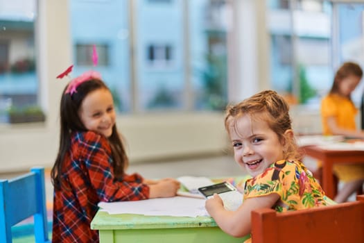 Creative kids during an art class in a daycare center or elementary school classroom drawing with female teacher