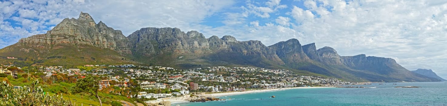 Mountain, travel and city by ocean in South Africa for tourism, traveling and global destination. Landscape, background and scenic view of beach by urban town for coastline, vacation and holiday.