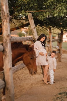 A pregnant woman with her son walks in the countryside in the summer.