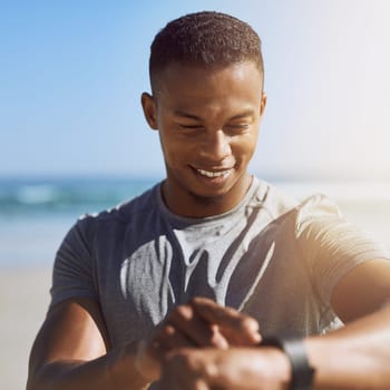 Tracking his goals as he goes. a sporty young man checking his smartwatch while exercising outdoors
