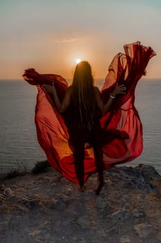 Woman sunset sea red dress, back view a happy beautiful sensual woman in a red long dress posing on a rock high above the sea on sunset