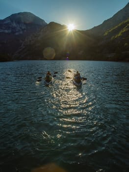 A group of friends enjoying fun and kayaking exploring the calm river, surrounding forest and large natural river canyons during an idyllic sunset