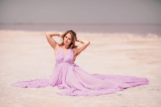 Pink lake woman. A woman in a pink dress sits on the salty shore of a pink lake and poses for a souvenir photo, creating lasting memories