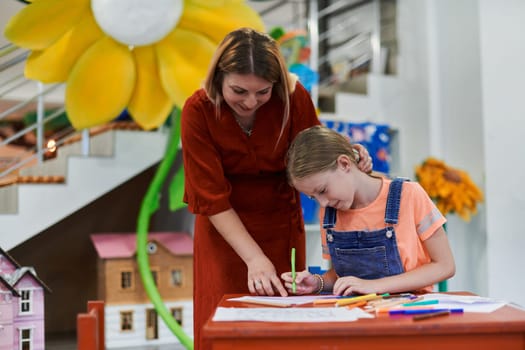 Creative kids during an art class in a daycare center or elementary school classroom drawing with female teacher. High quality photo