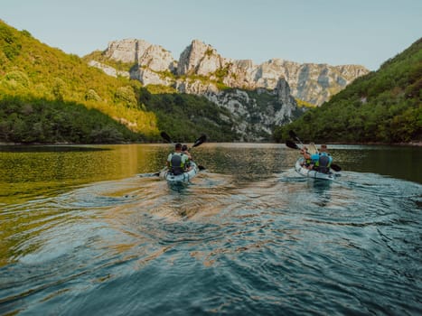 A group of friends enjoying having fun and kayaking while exploring the calm river, surrounding forest and large natural river canyons.