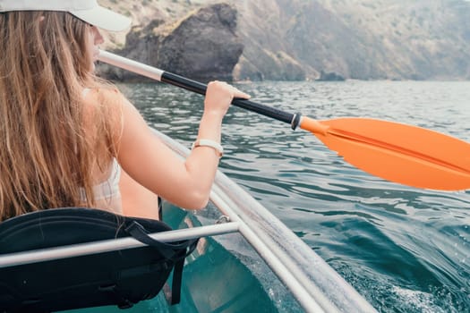 Woman in kayak back view. Happy young woman with long hair floating in transparent kayak on the crystal clear sea. Summer holiday vacation and cheerful female people having fun on the boat.