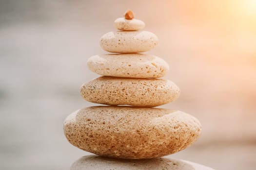 Pyramid stones on the seashore with warm sunset on the sea background. Happy holidays. Pebble beach, calm sea, travel destination. Concept of happy vacation on the sea, meditation, spa, calmness.