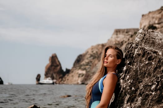 happy tourist in blue swimwear takes a photo outdoors to capture memories. The photo depicts a woman traveling and enjoying her surroundings on the beach, with volcanic mountains in the background