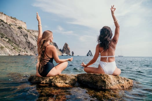 Woman sea yoga. Back view of free calm happy satisfied woman with long hair standing on top rock with yoga position against of sky by the sea. Healthy lifestyle outdoors in nature, fitness concept.