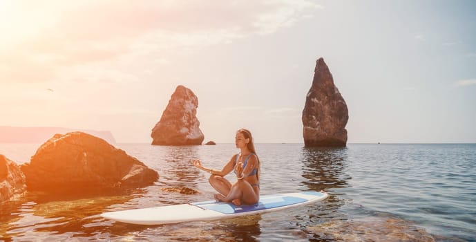 Woman sup yoga. Middle age sporty woman practising yoga pilates on paddle sup surfboard. Female stretching doing workout on sea water. Modern individual hipster outdoor summer sport activity