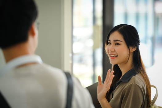 Pretty asian student woman waving hand for greeting to her friend in university campus. Youth lifestyle concept.