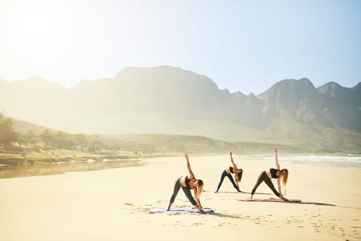 The practice of yoga is about gaining greater happiness and joy. three young women practicing yoga on the beach