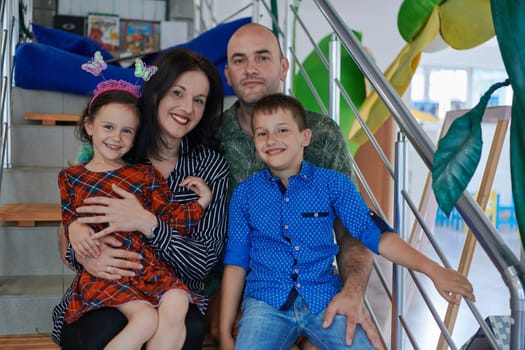 Portrait of a happy family. Photo of parents with children in a modern preschool classroom. Selective focus . High quality photo