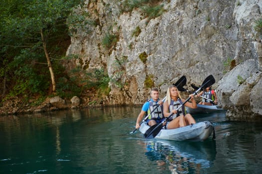 A group of friends enjoying having fun and kayaking while exploring the calm river, surrounding forest and large natural river canyons.