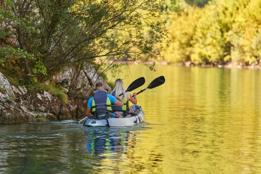 A young couple enjoying an idyllic kayak ride in the middle of a beautiful river surrounded by forest greenery.