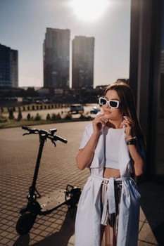 Stylish girl in glasses and a white summer coat in the city.