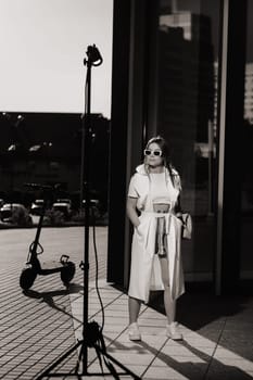 Stylish girl in glasses and a white summer coat in the city.