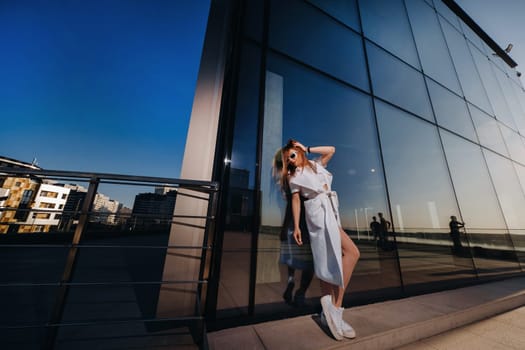 Stylish girl in glasses and a white summer coat in the city.