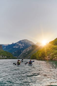 A group of friends enjoying fun and kayaking exploring the calm river, surrounding forest and large natural river canyons during an idyllic sunset