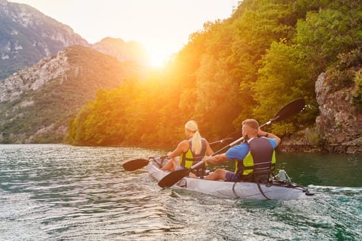 A group of friends enjoying fun and kayaking exploring the calm river, surrounding forest and large natural river canyons during an idyllic sunset