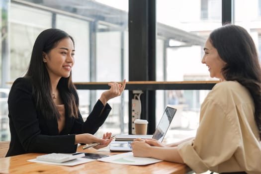 Happy two beautiful young Asian businesswoman standing discuss working together at office.