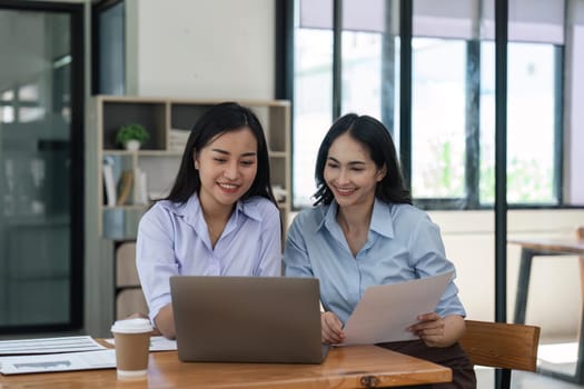 Happy two beautiful young Asian businesswoman standing discuss working together at office.