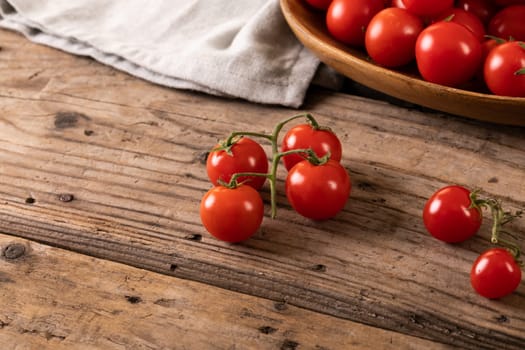High angle view of fresh red cherry tomatoes on wooden table. unaltered, organic food and healthy eating concept.