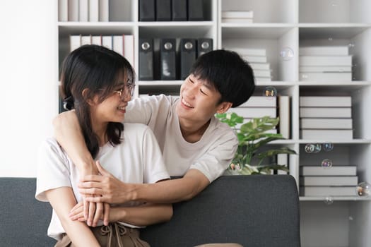 Smiling young couple embracing at office. Smiling man embracing from behind her happy girlfriend.
